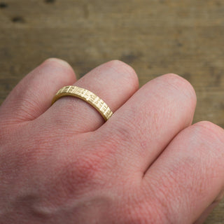 Back view of a 4mm 14k yellow gold men's wedding band demonstrating its matte textured design