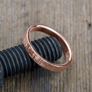 Close-up of a 4mm Textured Polished 14k Rose Gold Men's Wedding Ring, capturing its elegant design