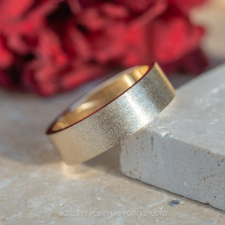 Men's Wedding Band made with 14k Yellow Gold, 6mm wide, displayed on a stand exhibiting the matte finishing