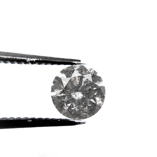 1.35 Carat Salt and Pepper Brilliant Cut Round Diamond held by tweezers, showcasing unique speckled inclusions, handcrafted with eco-friendly, conflict free materials.