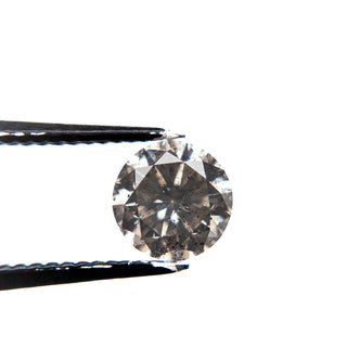Close-up of a 1.38 Carat Salt and Pepper Brilliant Cut Round Diamond held by tweezers, showcasing unique speckles and handcrafted eco-friendly quality.