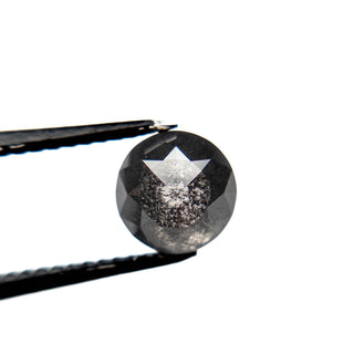 1.23 Carat Black Salt and Pepper Double Cut Round Diamond held by tweezers, showcasing its unique handcrafted, eco-friendly design with speckled inclusions.