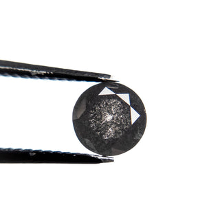 1.23 Carat Black Salt and Pepper Double Cut Round Diamond held by tweezers, showcasing its unique speckled inclusions and eco-friendly, handcrafted design.