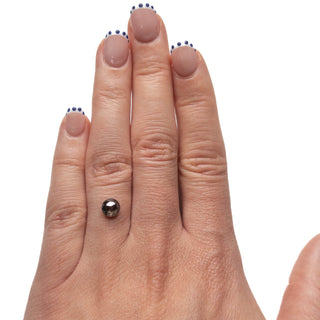 1.23 Carat Black Salt and Pepper Double Cut Round Diamond resting on a hand with natural nails featuring subtle dark dot accents, showcasing unique eco-friendly jewelry.