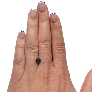 1.23 Carat Black Salt and Pepper Double Cut Round Diamond resting on a hand with neutral-toned nails, showcasing a unique and eco-friendly conflict free diamond.