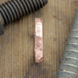 Close up view of 14k Rose Gold, 4mm wide Mens Wedding Band with intricate hammered matte finish
