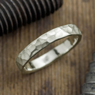 Closeup view of a 4mm 14k white gold men's wedding ring with a hammered matte finish