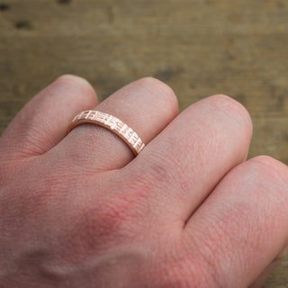 High-resolution image of a 4mm 14k rose gold mens wedding band with a distinct matte texture
