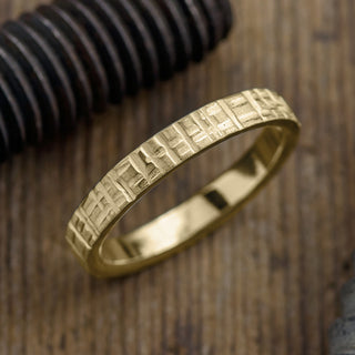 Close-up view of a 14k yellow gold men's wedding band with 4mm width and a textured matte finish
