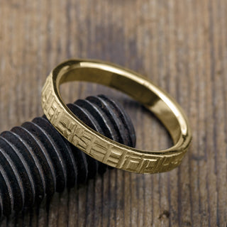 Side view of a 4mm men's wedding band made of 14k yellow gold exhibiting a matte textured surface