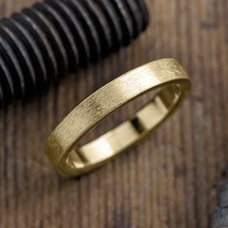Men's 4mm 14K Yellow Gold wedding band with a sophisticated matte finish displayed on a neutral background