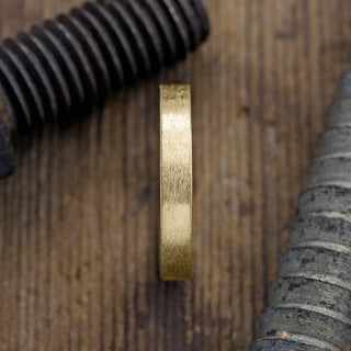 Close up view of a 4mm 14K Yellow Gold Men's Wedding ring featuring a modern matte finish