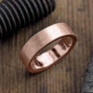 Elegant 14K Rose Gold Men's Wedding Band, Matte Finish and 6mm width showcased on a stand