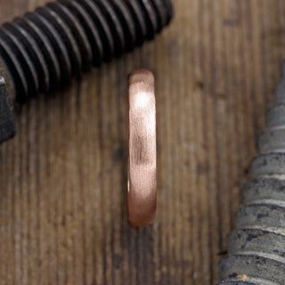 Close-up of 4mm 14k rose gold men's wedding band, highlighting its half round shape and matte finish
