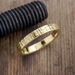 Man's 4mm textured 14k yellow gold wedding band with a high-polished finish on a white background