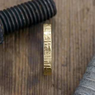 Close-up view of the intricate texture on a 14k yellow gold men's wedding band