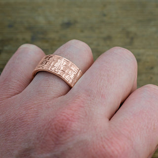 Distinctive men's wedding band showcasing a 10mm 14k Rose Gold band with a Textured Polished design
