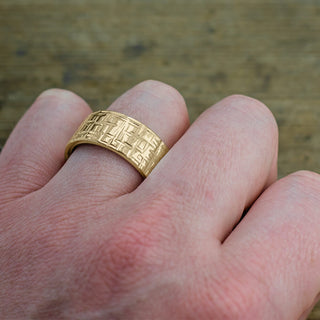 Close-up detail of textured, polished 10mm 14k yellow gold men's wedding ring, focusing on the quality of the finish