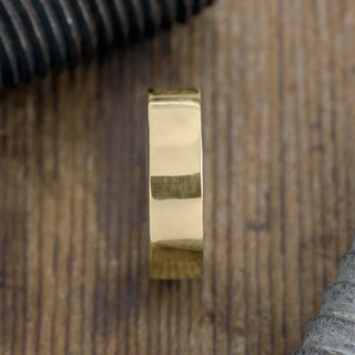 14k Yellow Gold Mens Wedding Band perched on black background, highlighting the 6mm thickness