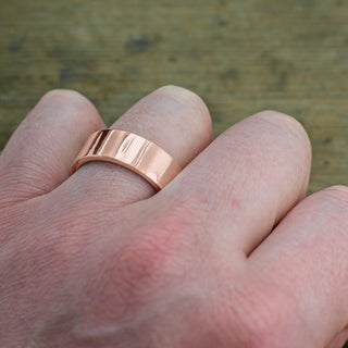 Close-up of a 14K rose gold 8mm men's wedding ring, bright and polished surface, product view D