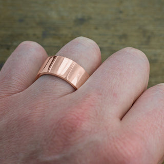 Close up detail of a highly polished 10mm mens wedding ring made from 14k rose gold