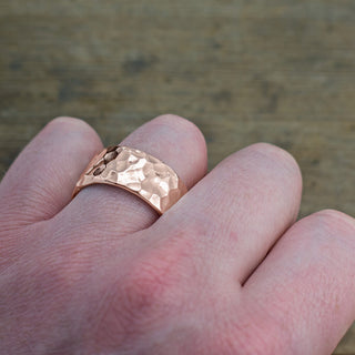 Elegant 14k rose gold men's wedding ring with a unique hammered texture, seen from the side