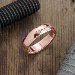 Detailed view of 14k rose gold men's wedding ring, 6mm in width with a polished half round look