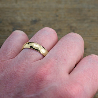 Sophisticated 6mm 14k yellow gold men's wedding band, half-round and polished, showcased against a dark background