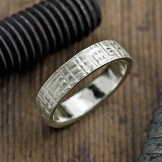 Close-up view of a 6mm 14k white gold mens wedding band featuring a textured matte finish